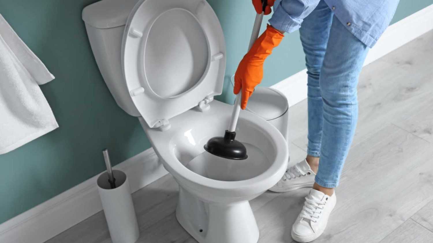 Woman cleaning toilet bowl in bathroom