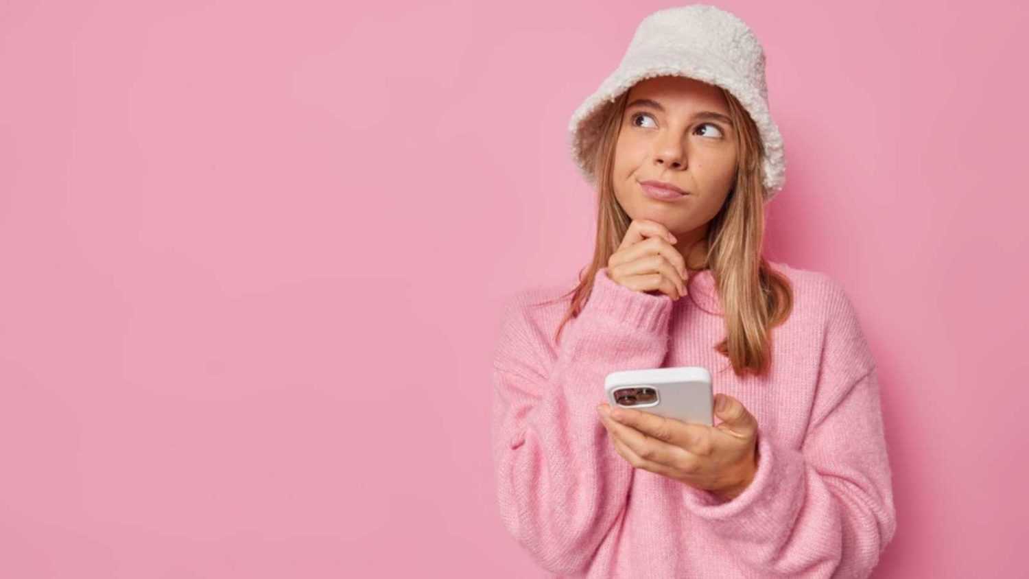 Woman thinking with mobile in hands