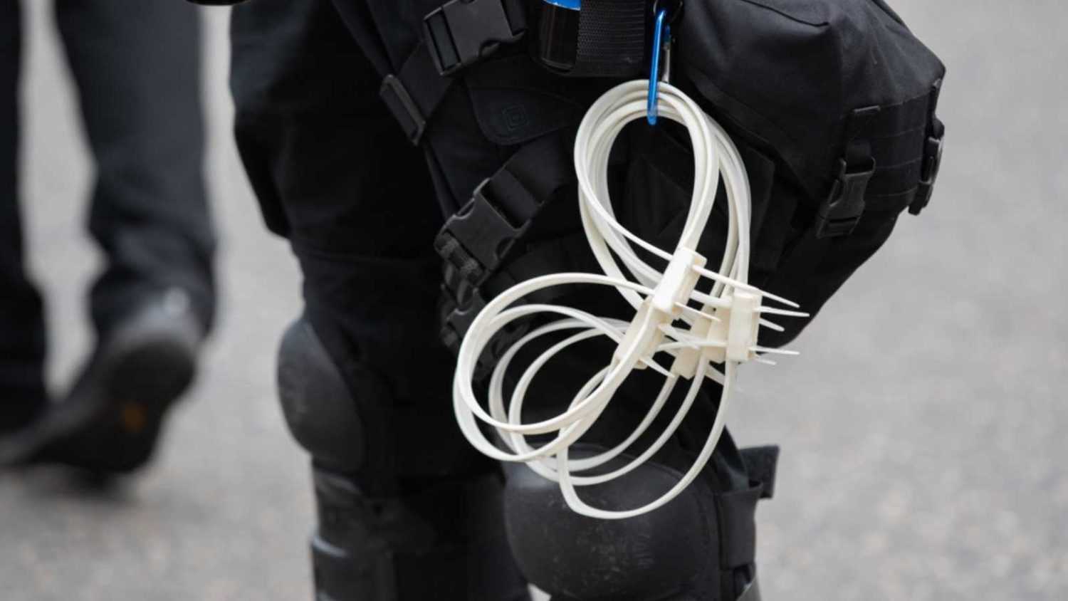 Double cuff zip tie plastic handcuffs hanging from a police belt