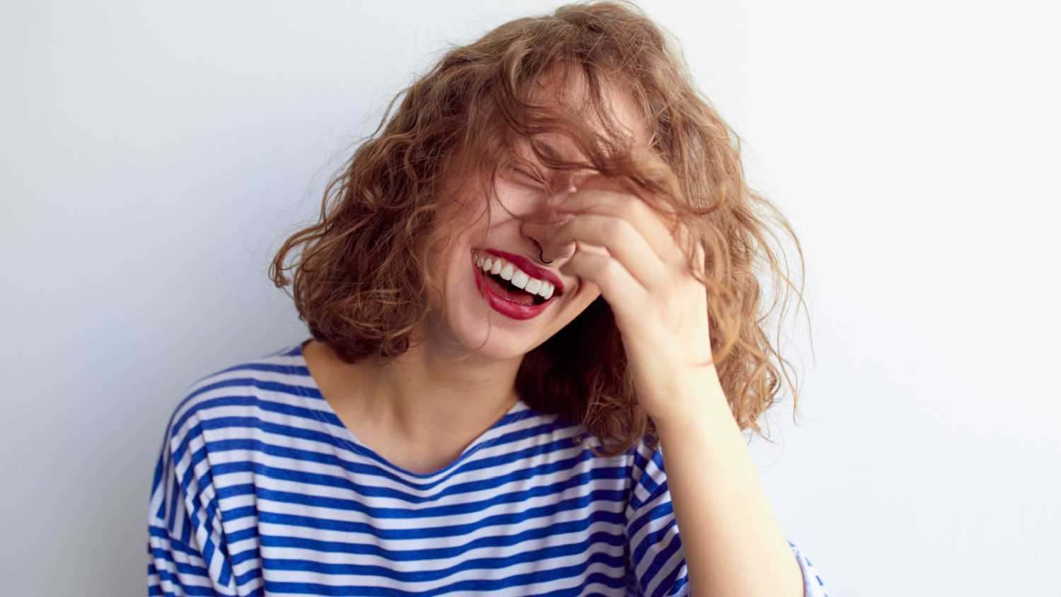 woman laughing covering face