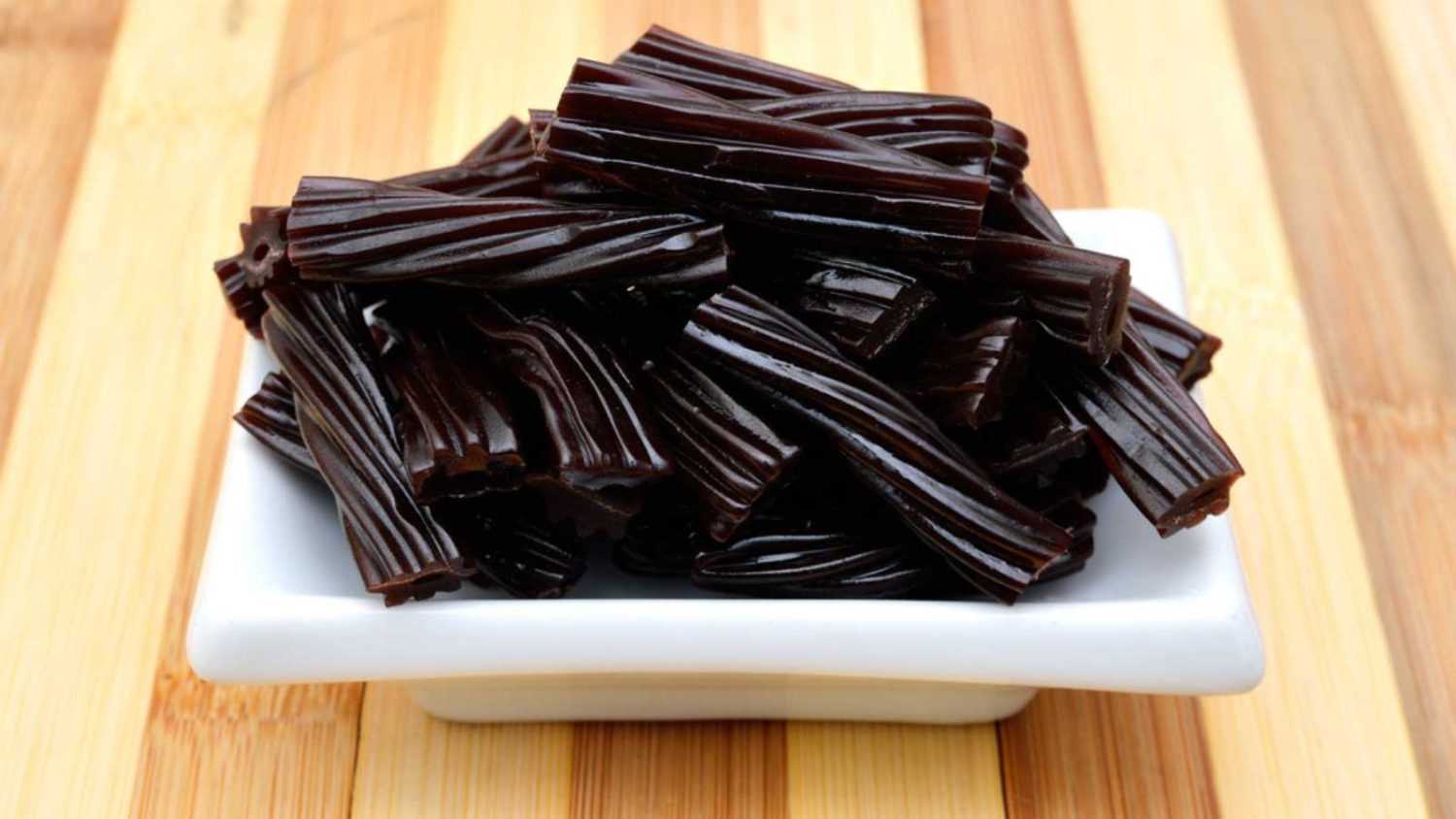 Black Licorice Candy shaped like a twisted rope in plate on wooden board