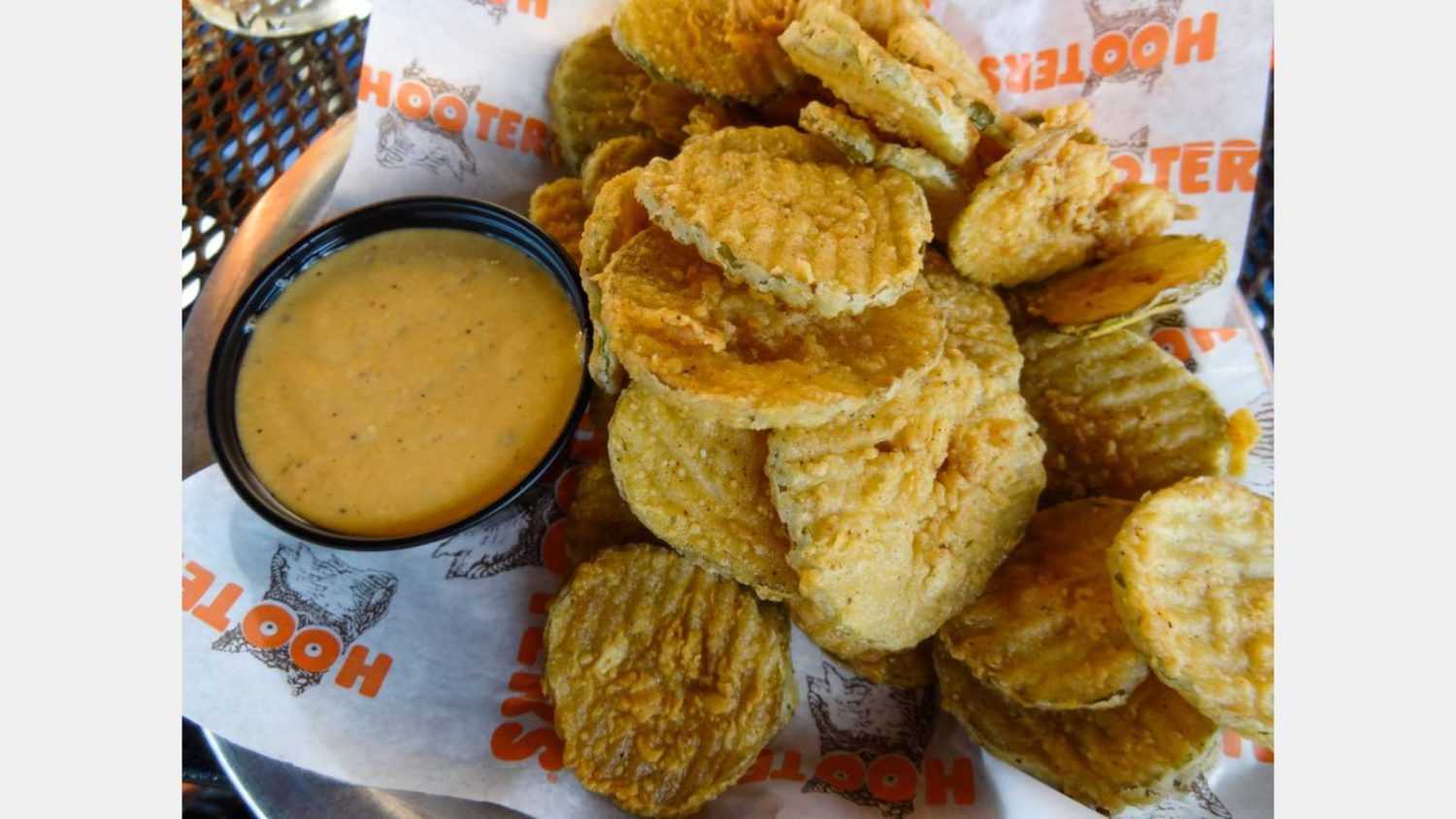 Atlanta, Georgia / USA - August 22 2012: Closeup of pile of delicious dill pickle slices, battered and deep fried, with tangy dipping sauce on plate served at Hooters restaurant
