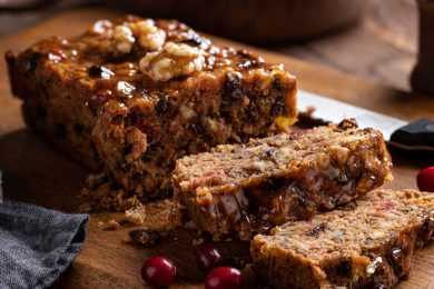 Fruitcake loaf sliced on a rustic wooden cutting board