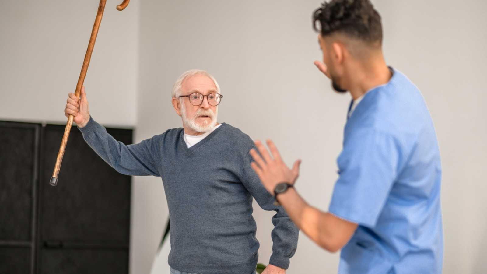 Exasperated pensioner threatening his caretaker with his cane
