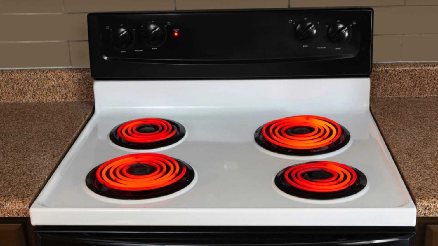 Horizontal shot of the stovetop of an electric range with all the burners turned to high and glowing red.